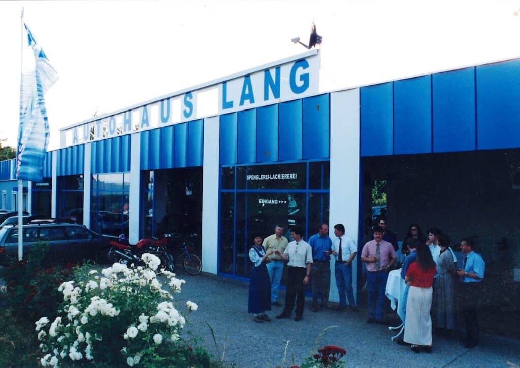 Das Autohaus Lang in St. Anna am Aigen am Tag der Eröffnung im Jahr 1998 . Ronald und Maria Lang stehen mit vielen Kunden und Kundinnen vor dem Eingang.