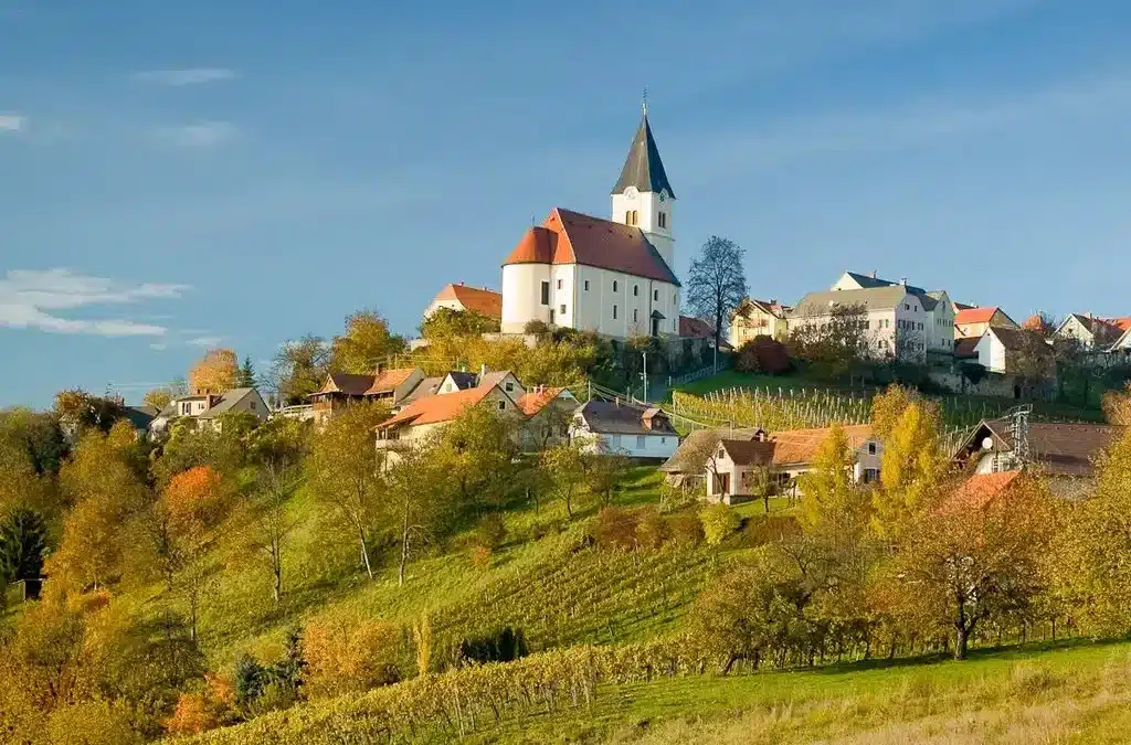 Ein Foto von Sankt Anna am Aigen,. Man sieht dir Kürche af einem Hügel und der Wanderwag zur Kirche ist mit Weingärten geziert.